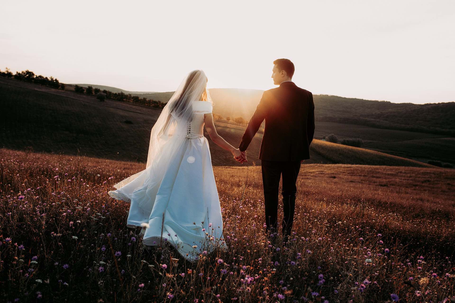 Bride and groom walking in a field at sunset on the Archangel Law Group website Family Law page