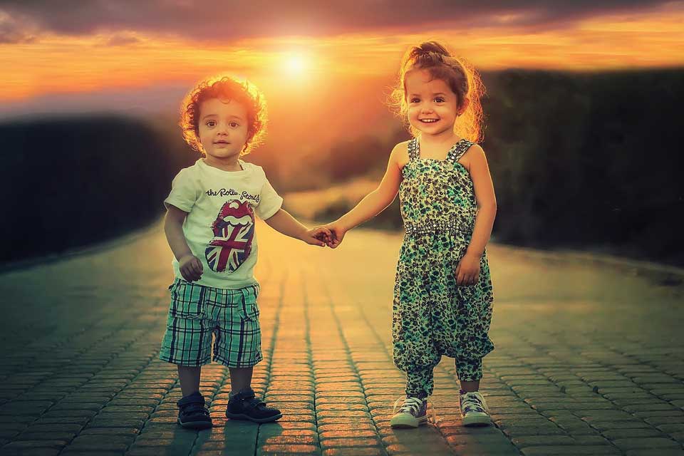 Two young children holding hands at sunset for family law
